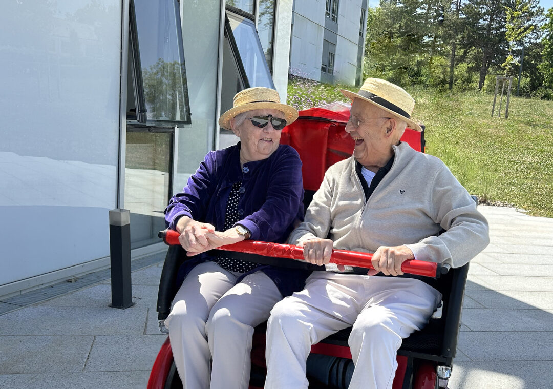 Résidents profitant d'une balade en vélo adapté dans les extérieurs de l'établissement.